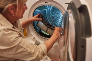 Woman cleaning dryer lint filter.